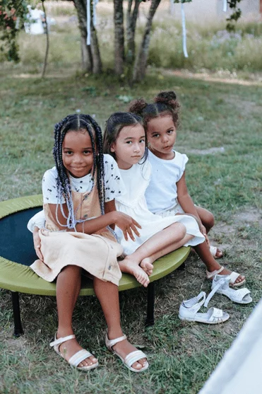 Young girls sitting on a trampoline.